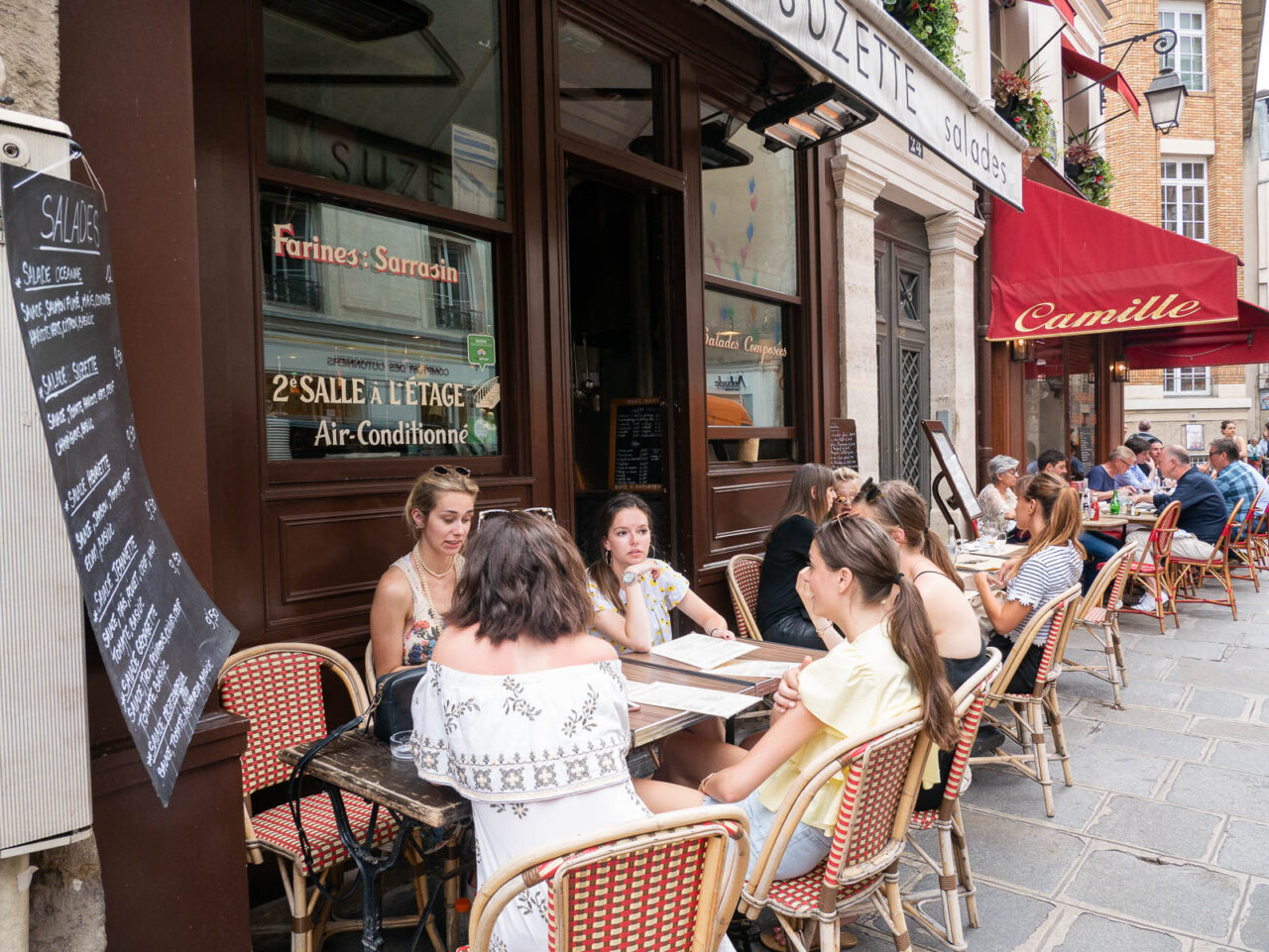 People dining outside a cafe in Le Marais neighborhood Paris