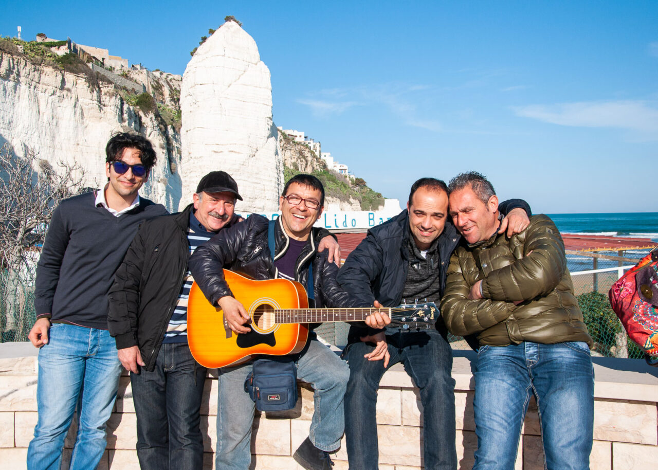 Group of Italian men with guitar next to Pizzomunno.