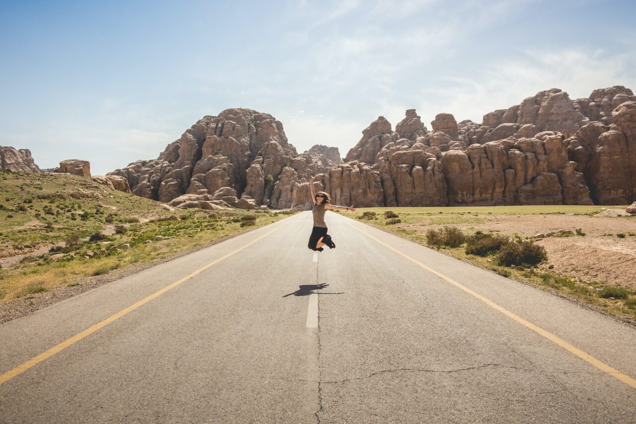 Woman jumping on a road in front of the painted house, Jordan