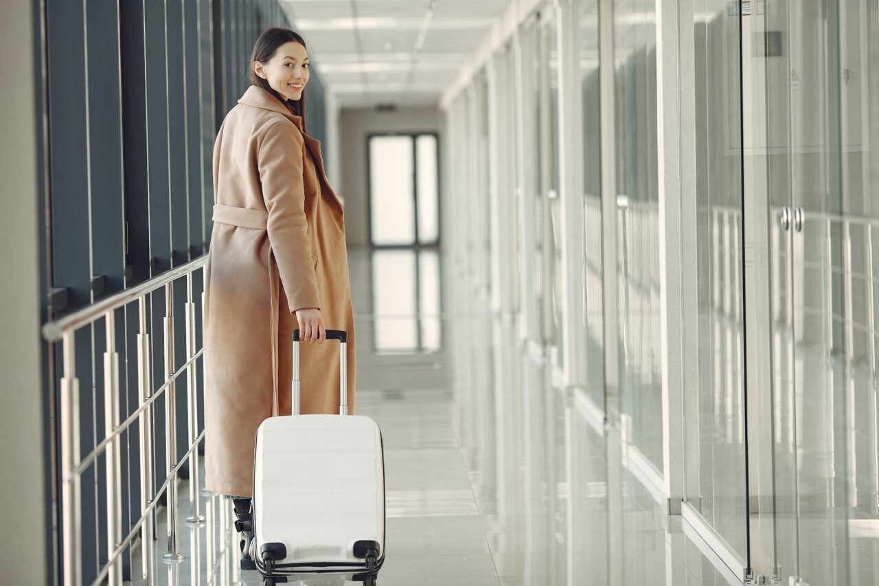 Stylish woman pulling suitcase at the airport