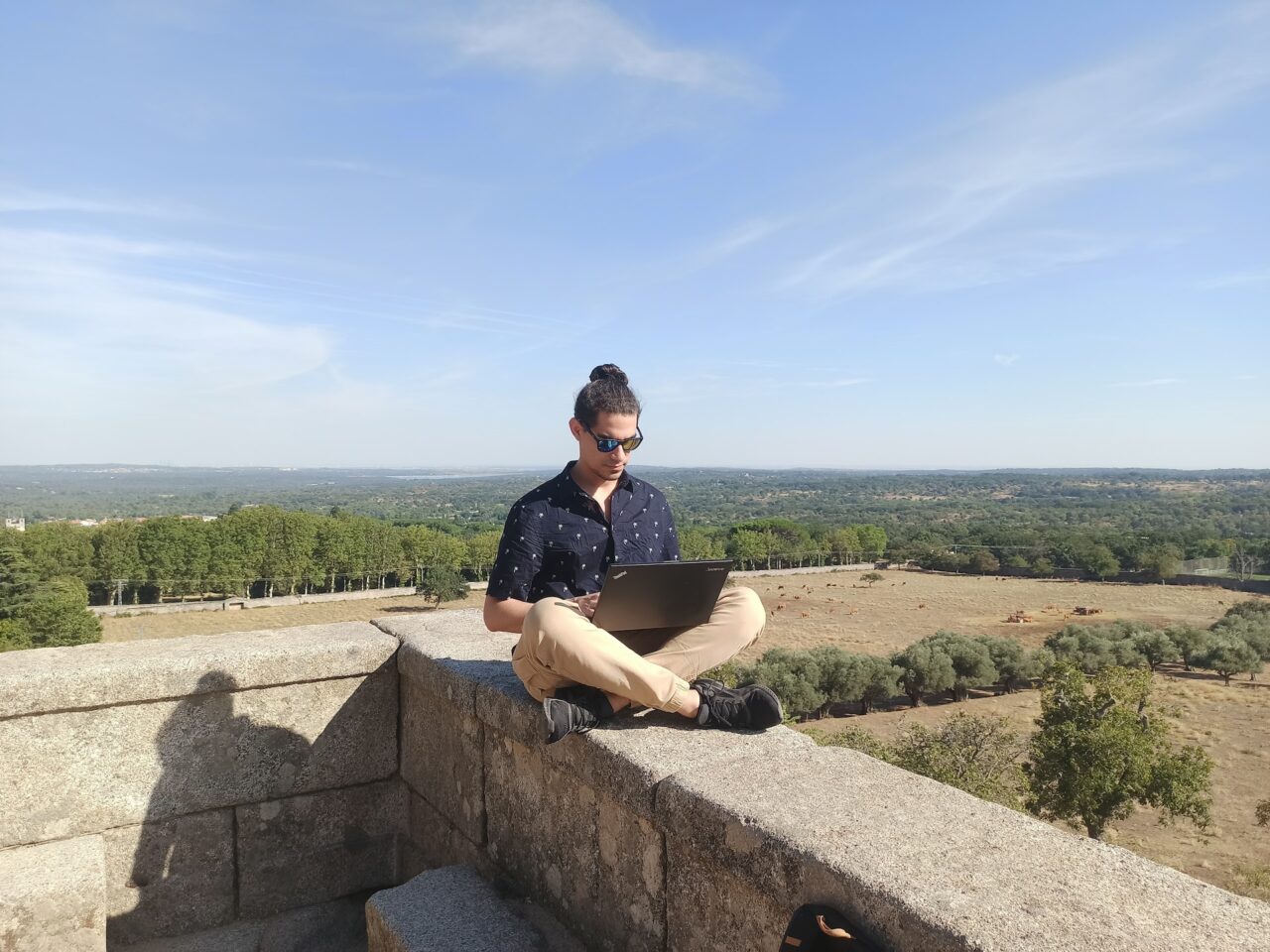 Digital nomad sitting on a wall with laptop