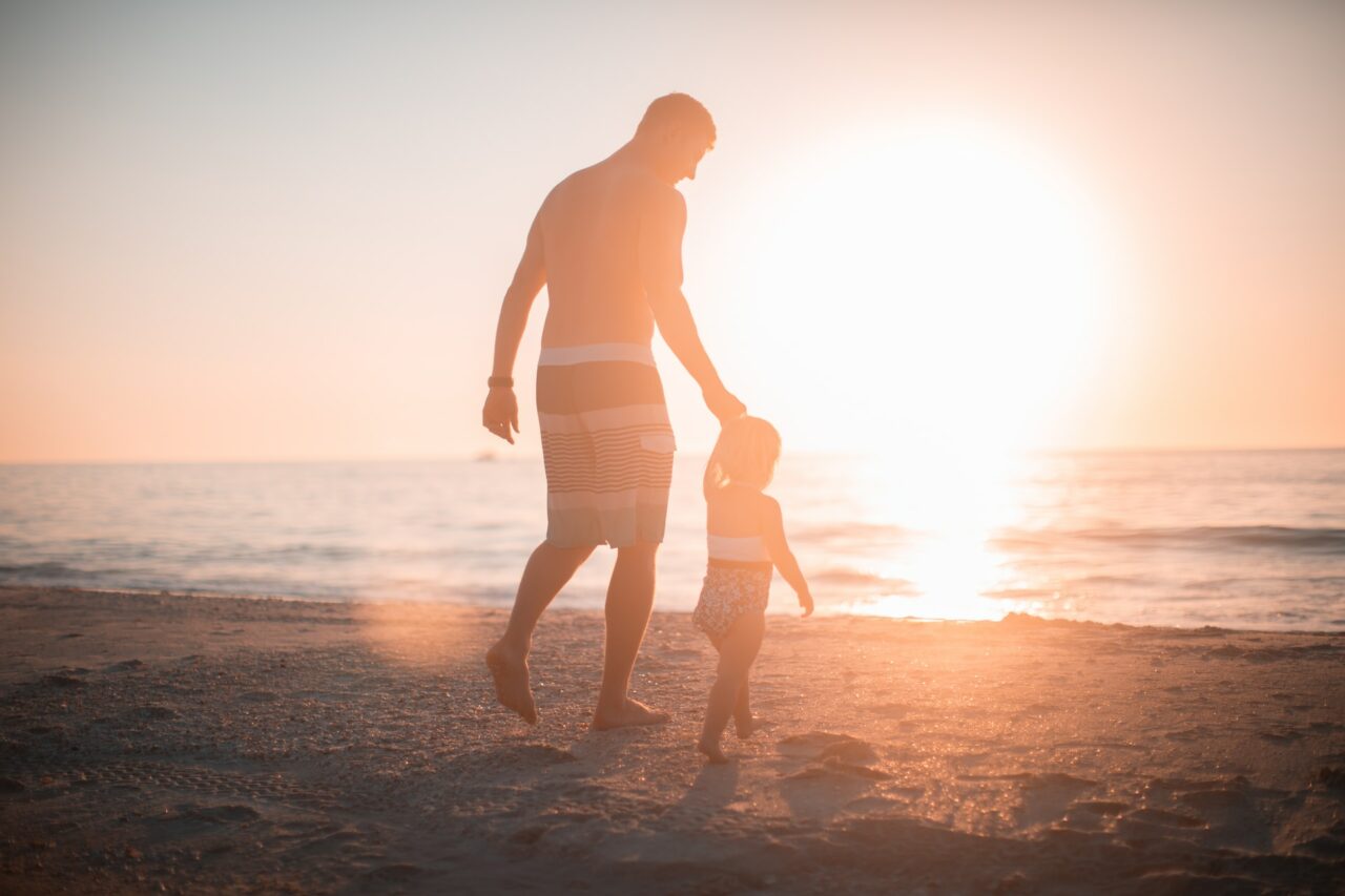 Man holding child's hand on the beach