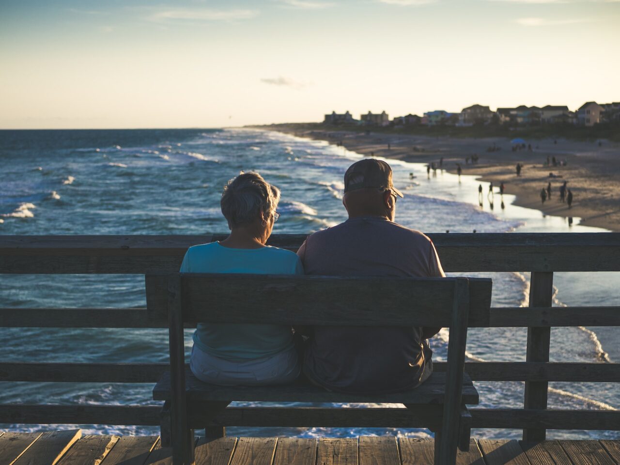 Two elderly retirees on a bench looking out at the beach