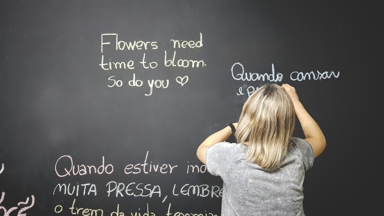 Woman writing on a chalk board in different languages