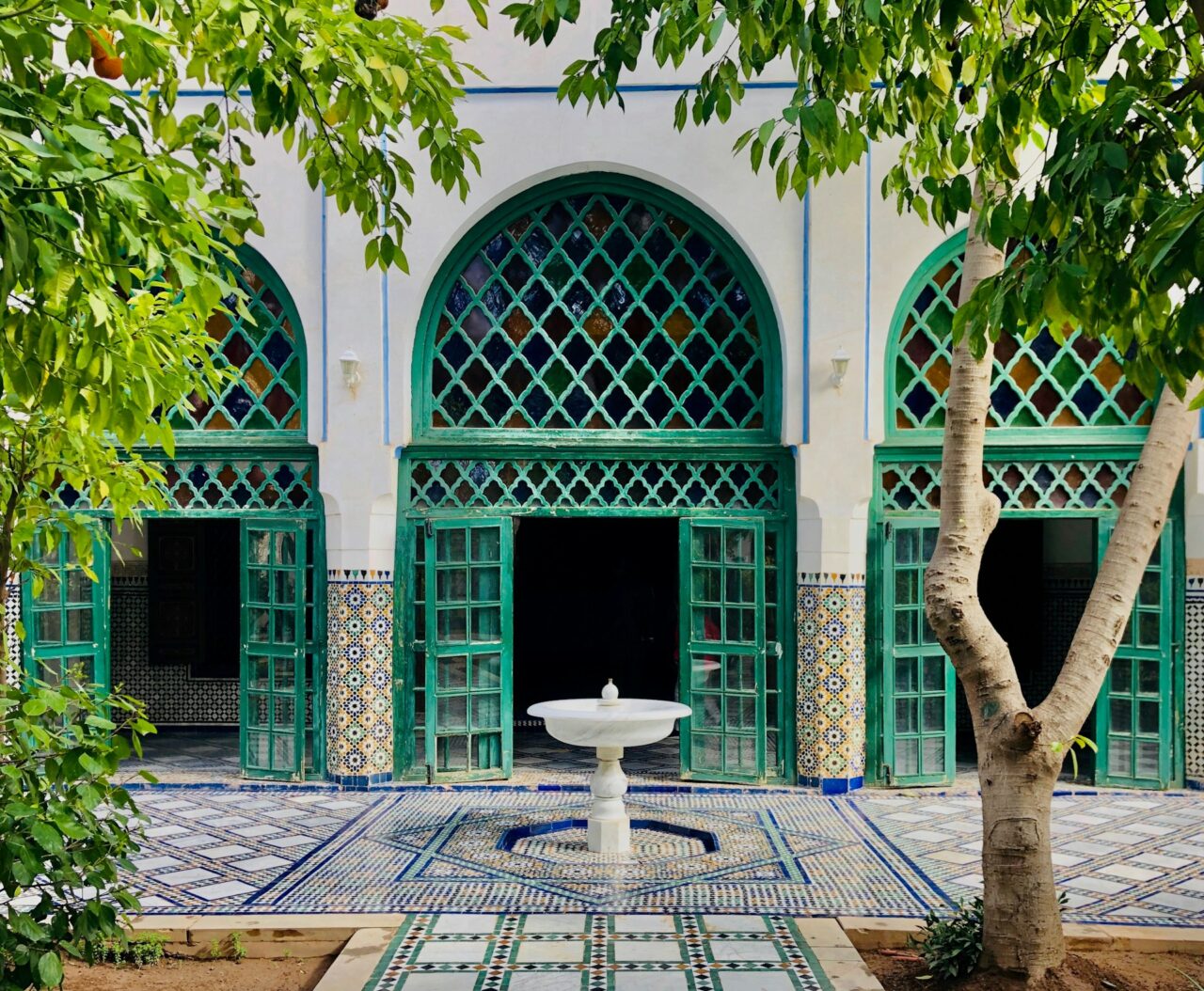 White building with green archways, fountain and tiled floor in Marrakech