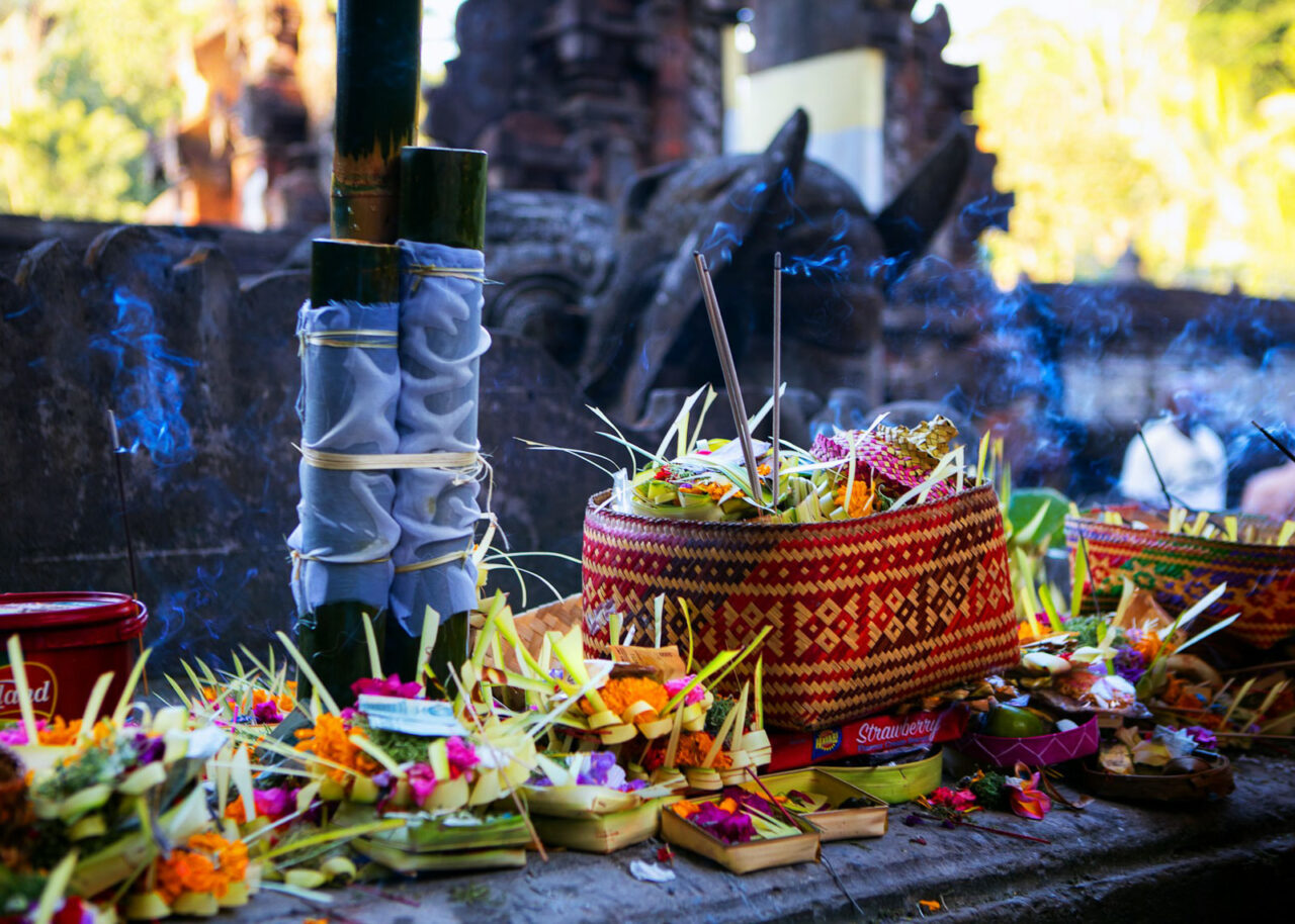 Colorful canang sari with incense at a temple in Bali