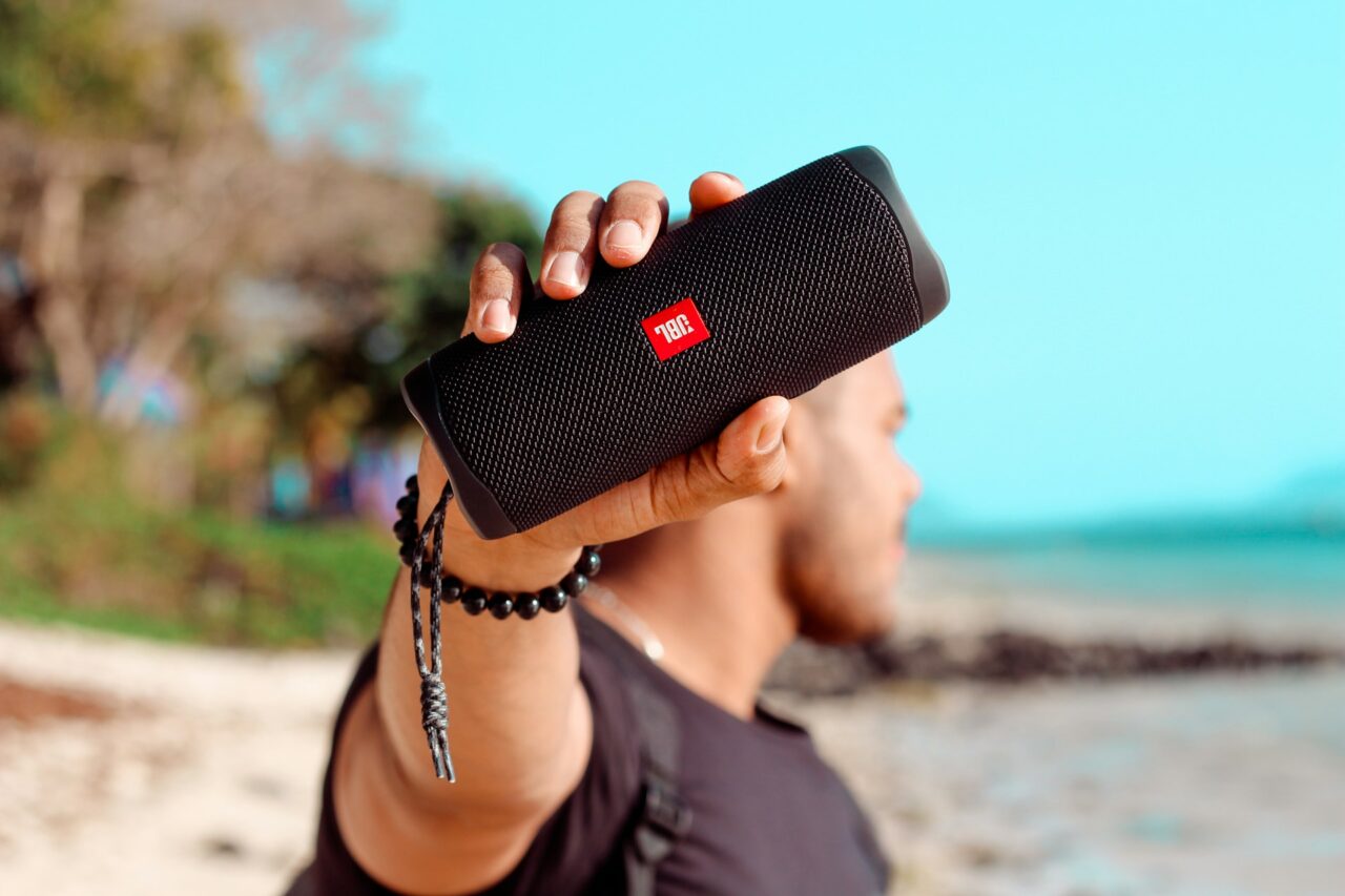 Man holding a JBL Bluetooth speaker on a beach