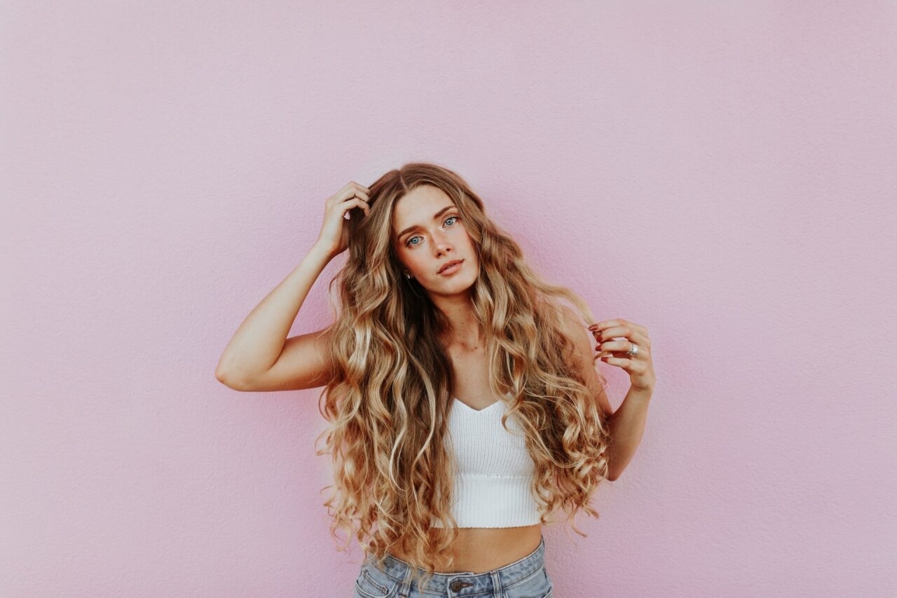 Woman with long curly hair against pink background