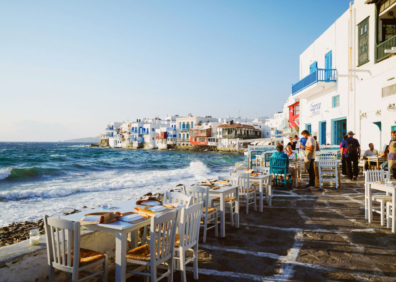 Restaurant on the water with Little Venice in the background in Mykonos Old Town, Greece