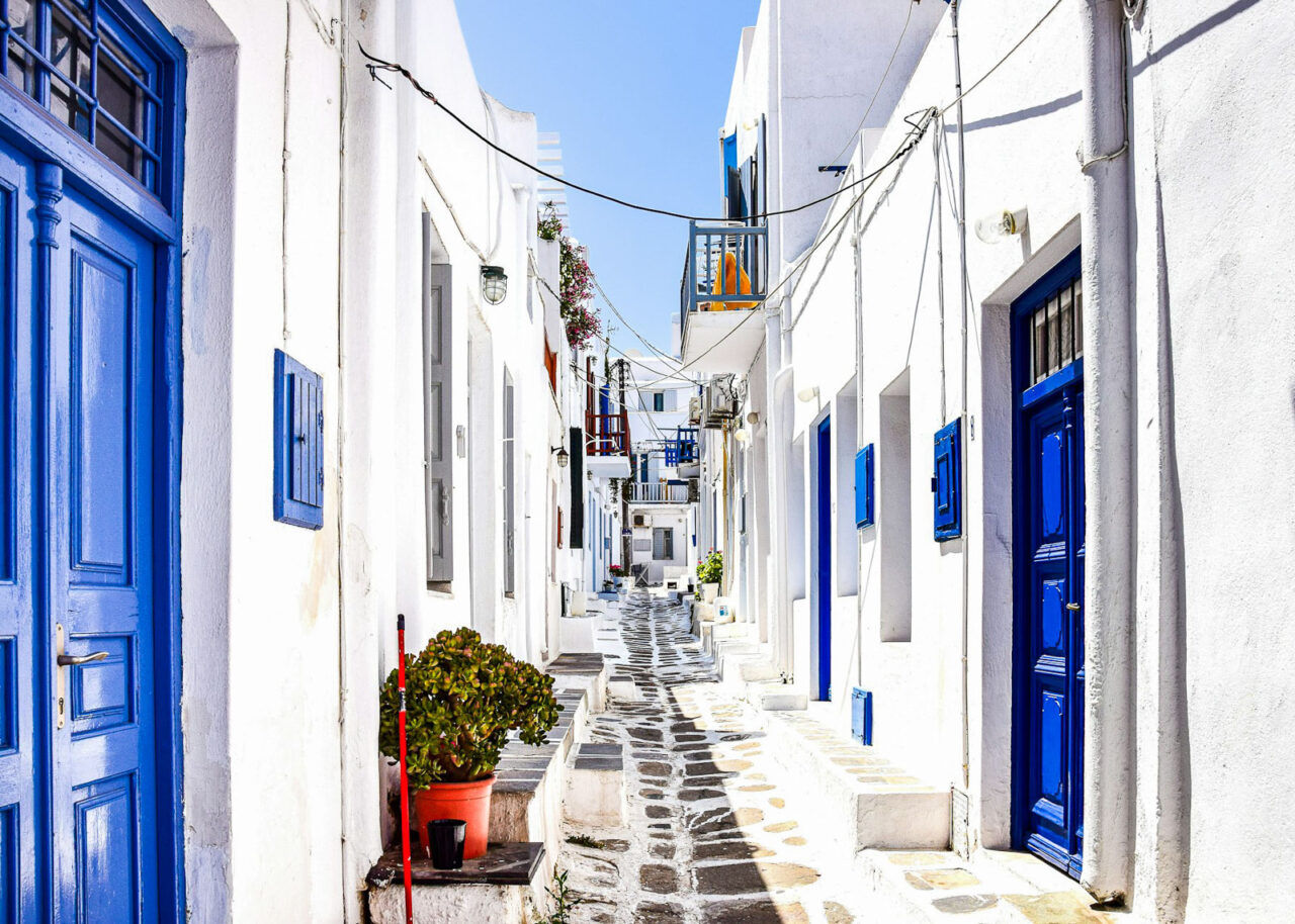 Street with white buildings and blue doors in Mykonos, Greece