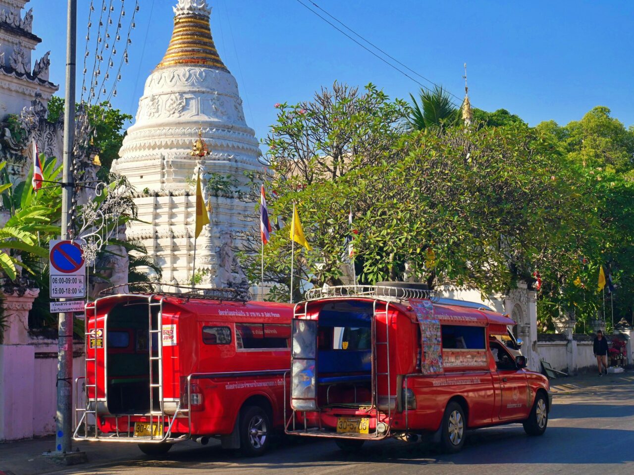 Red Songthaew parked next to a temple in Thailand