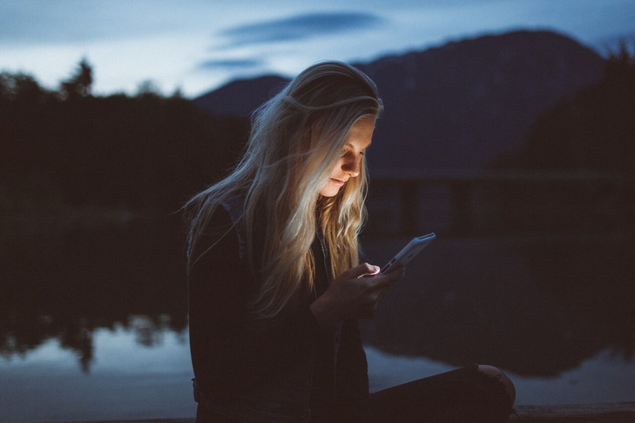 Blonde woman texting at night in the outdoors