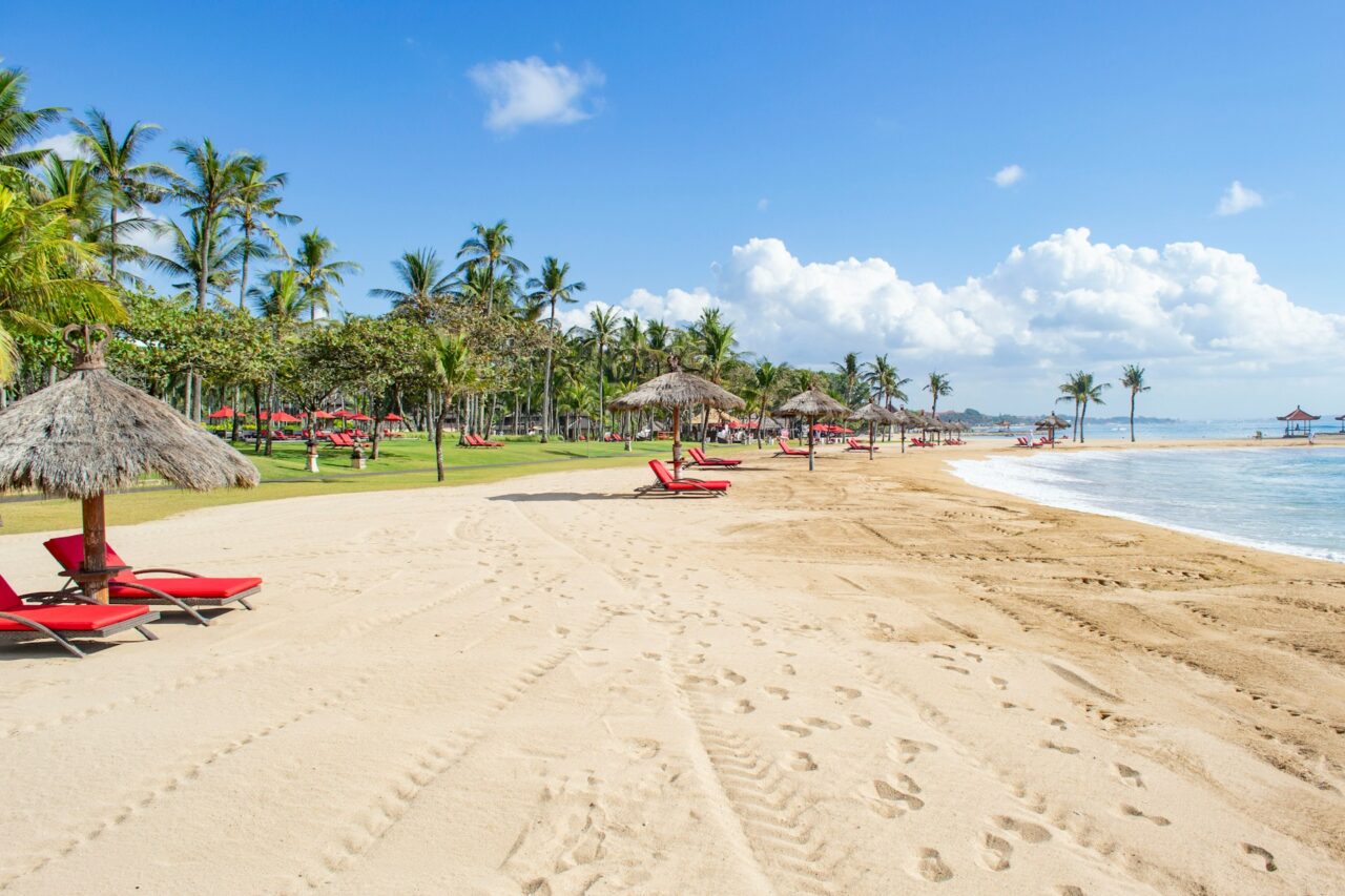 Sandy beach with red lounge chairs in Bali