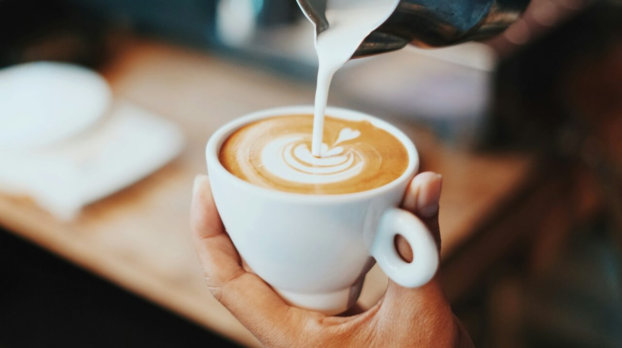 Close up of person pouring a latte coffee