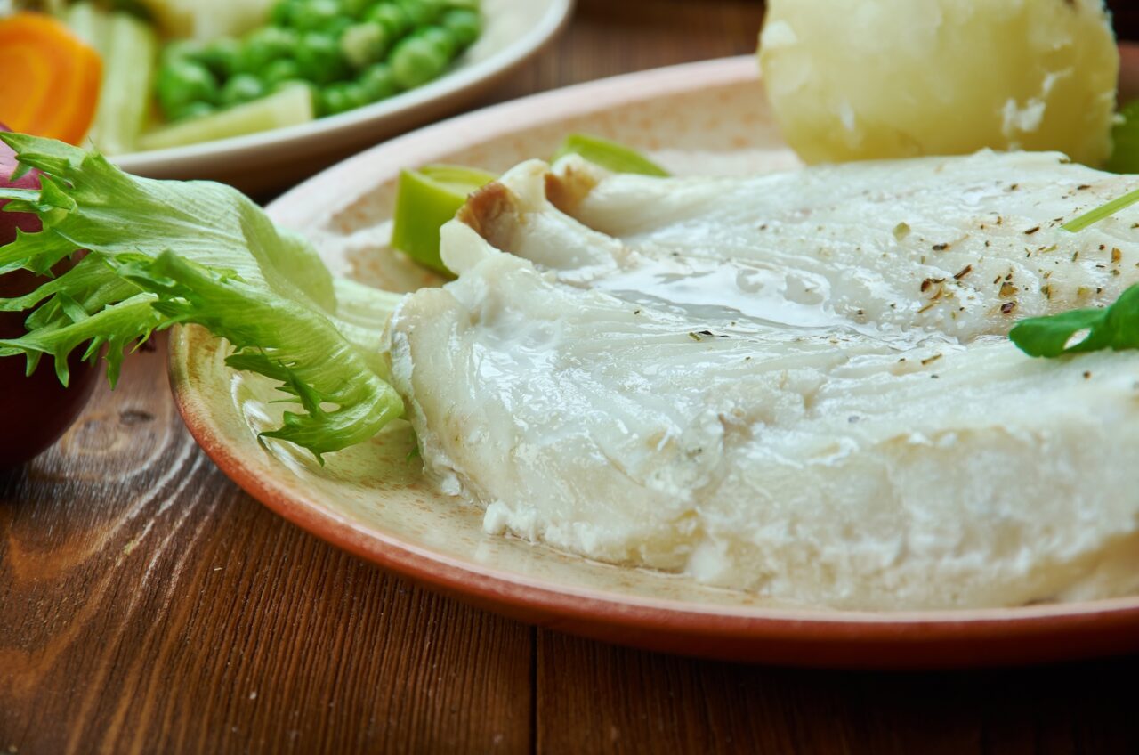 Lutefisk white fish on a plate with lettuce and potatoes