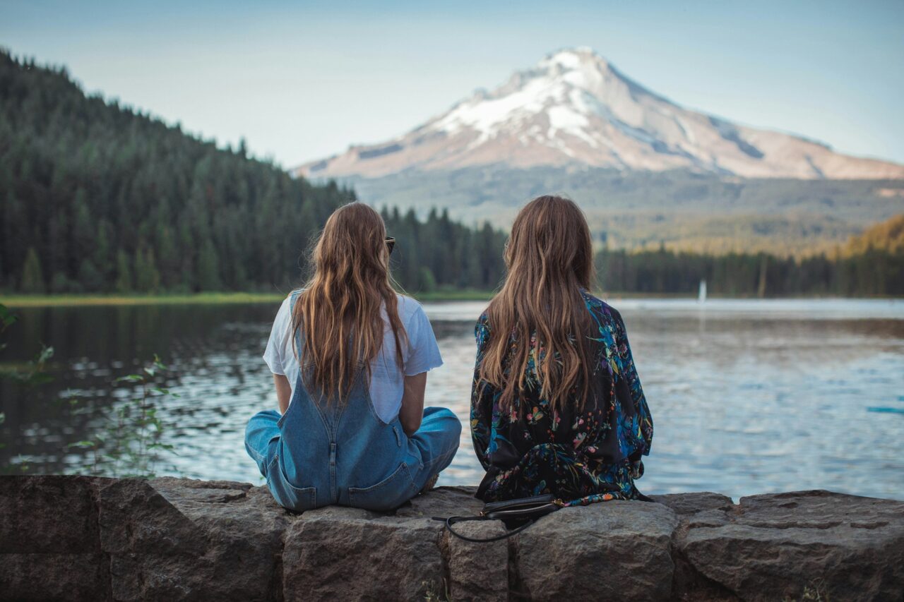Two women sitting in front of mount hood