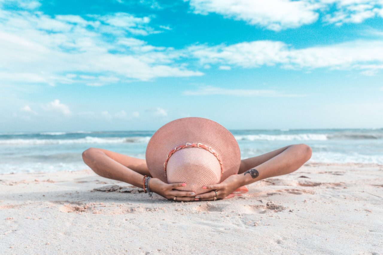 Person wearing a hat laying on the beach in Playa del Carmen Mexico