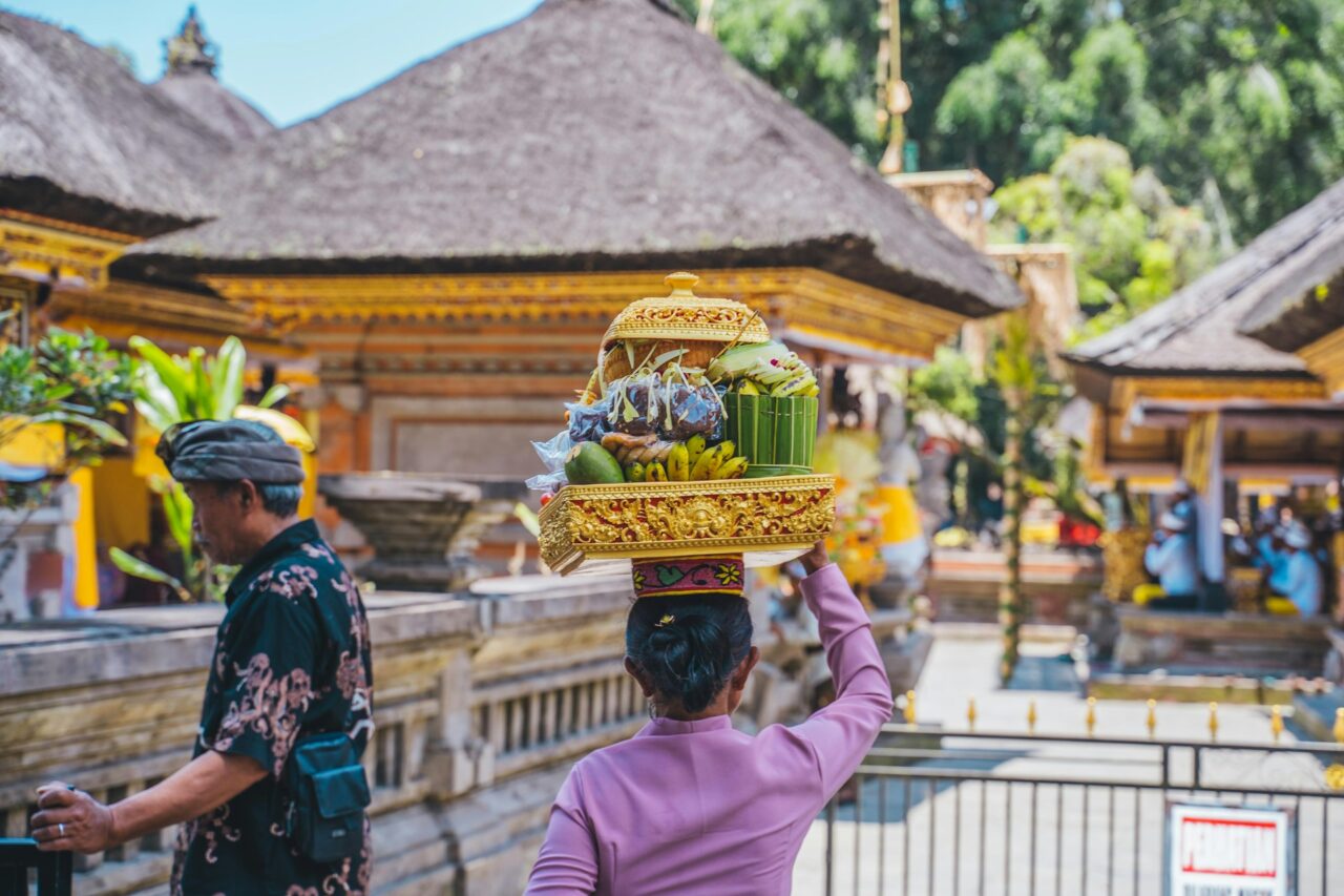 Woman carrying offerings on her head at temple Tirta Empul in Bali