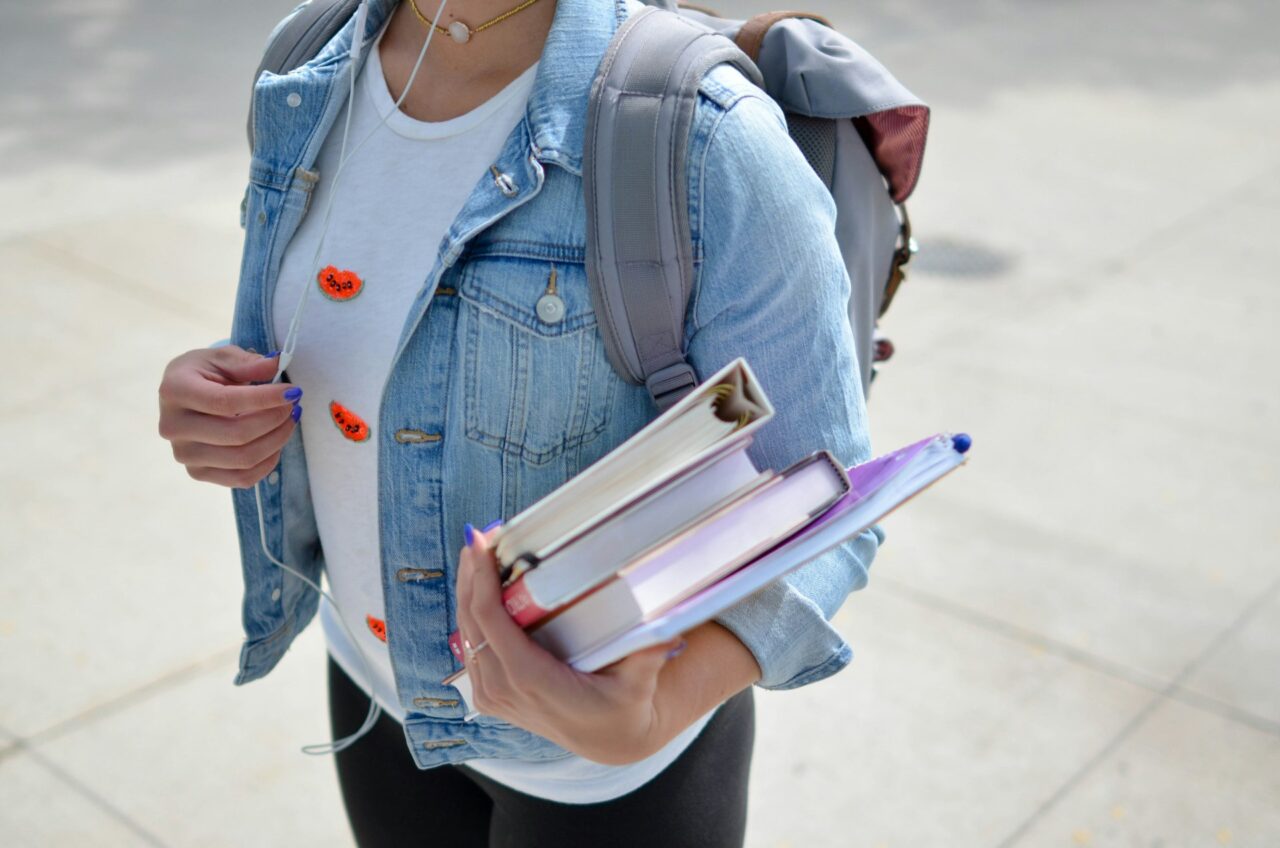 Girl wearing a denim jacket holding books