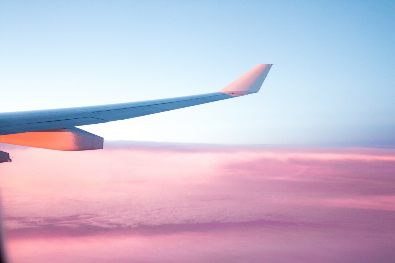 Plane wing over a pink sky