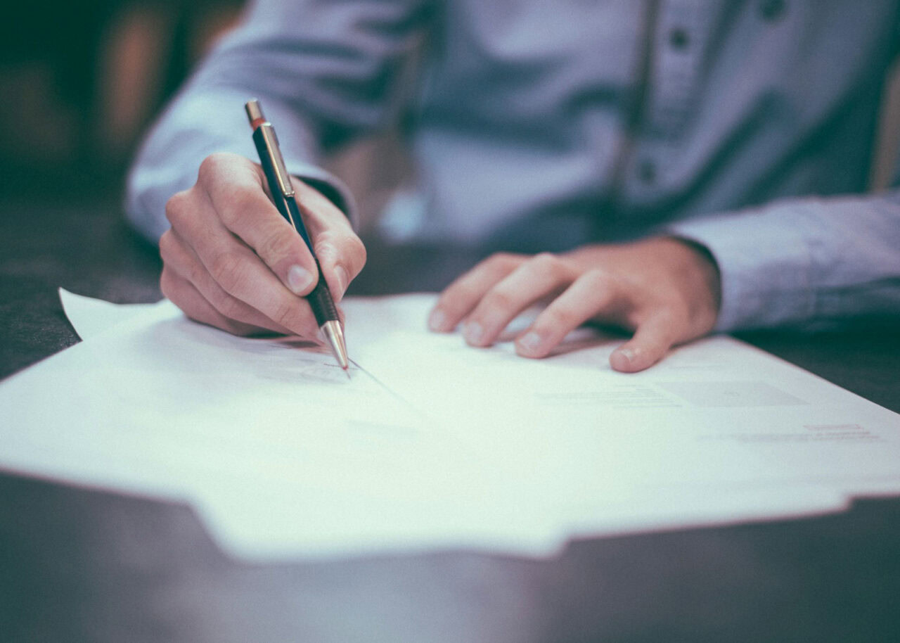 Close up of a man's hands signing a document