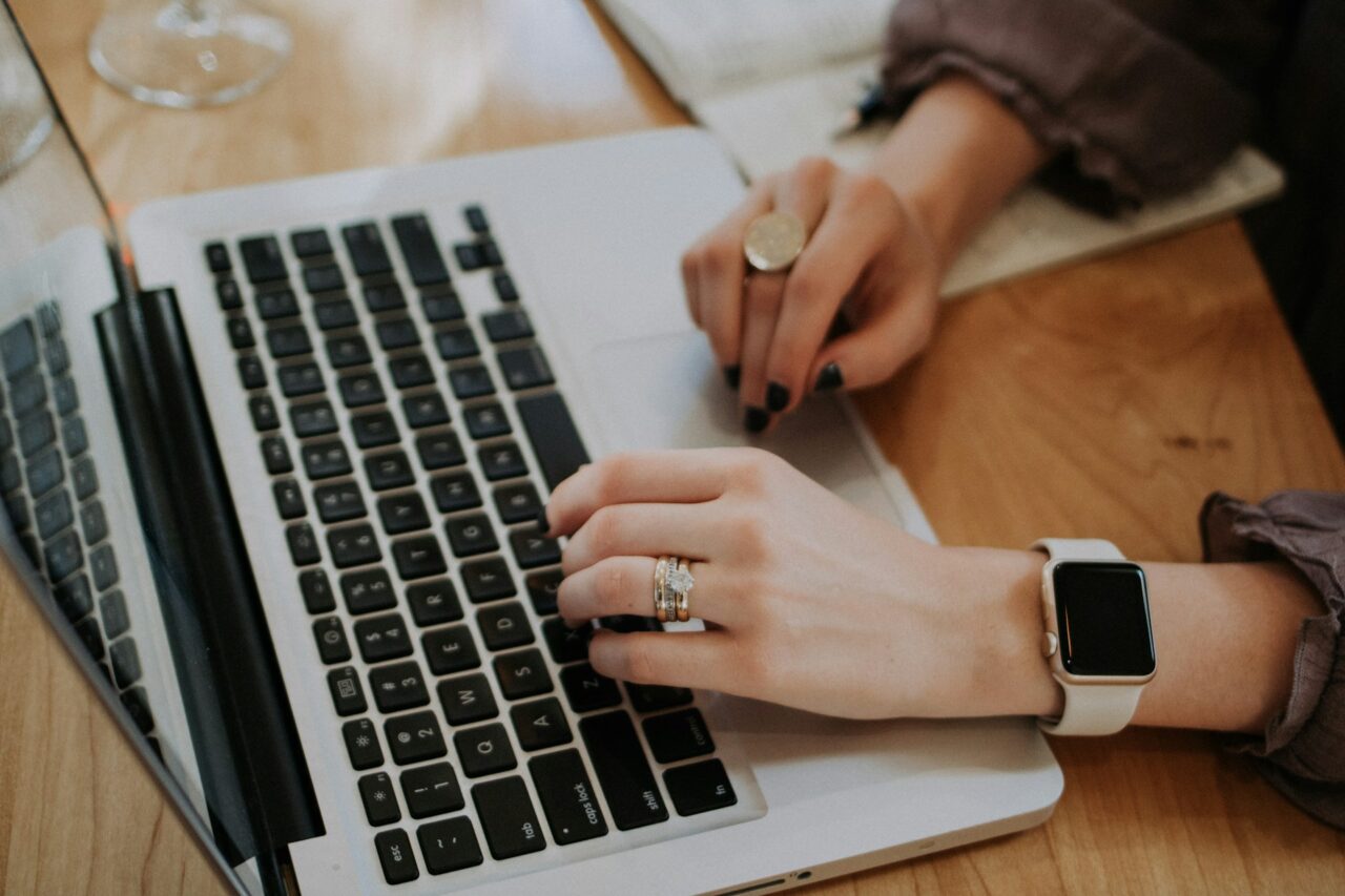 Woman's hands typing on a Macbook laptop