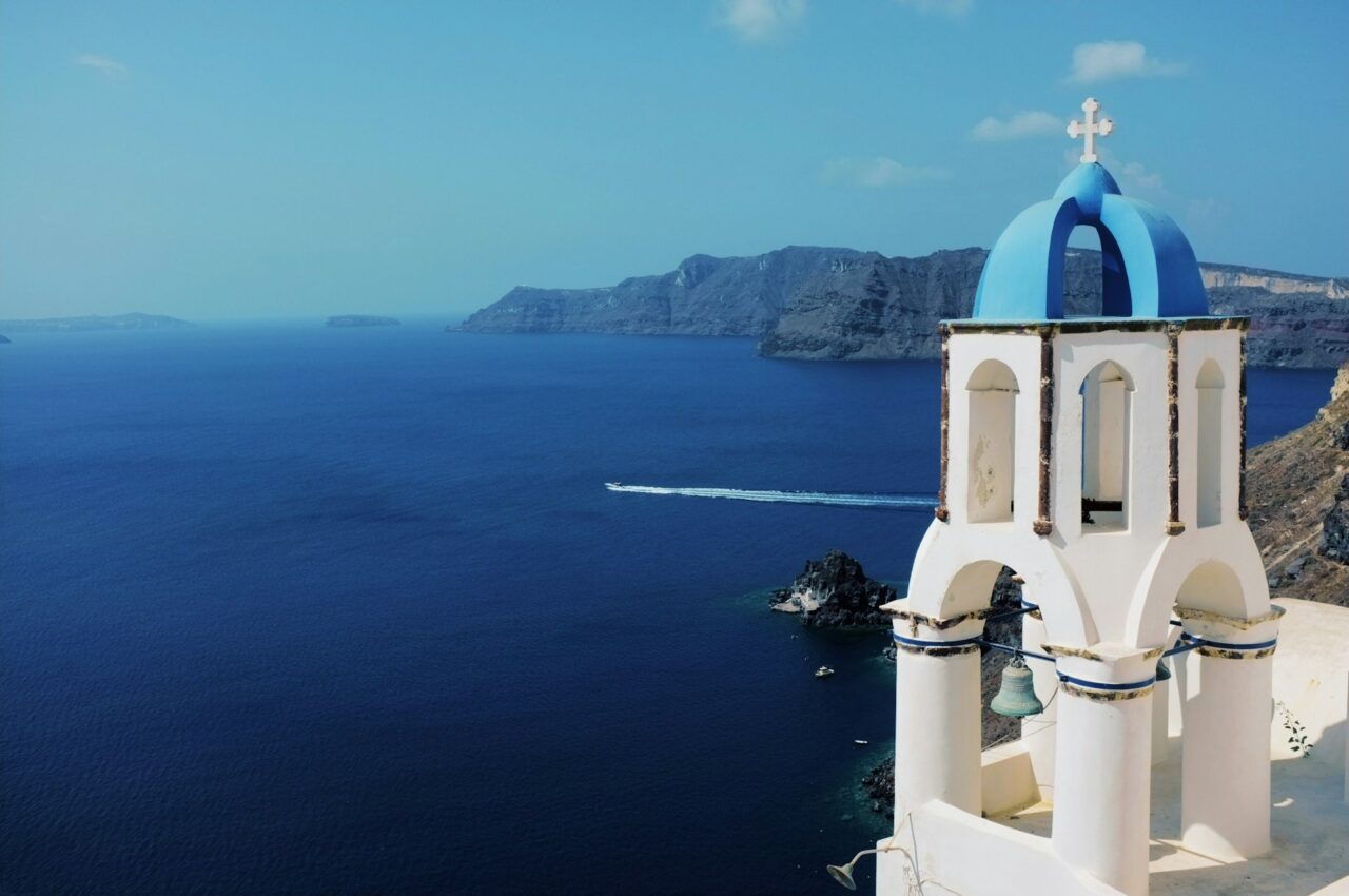 White church with blue dome next to the sea in Santorini, Greece