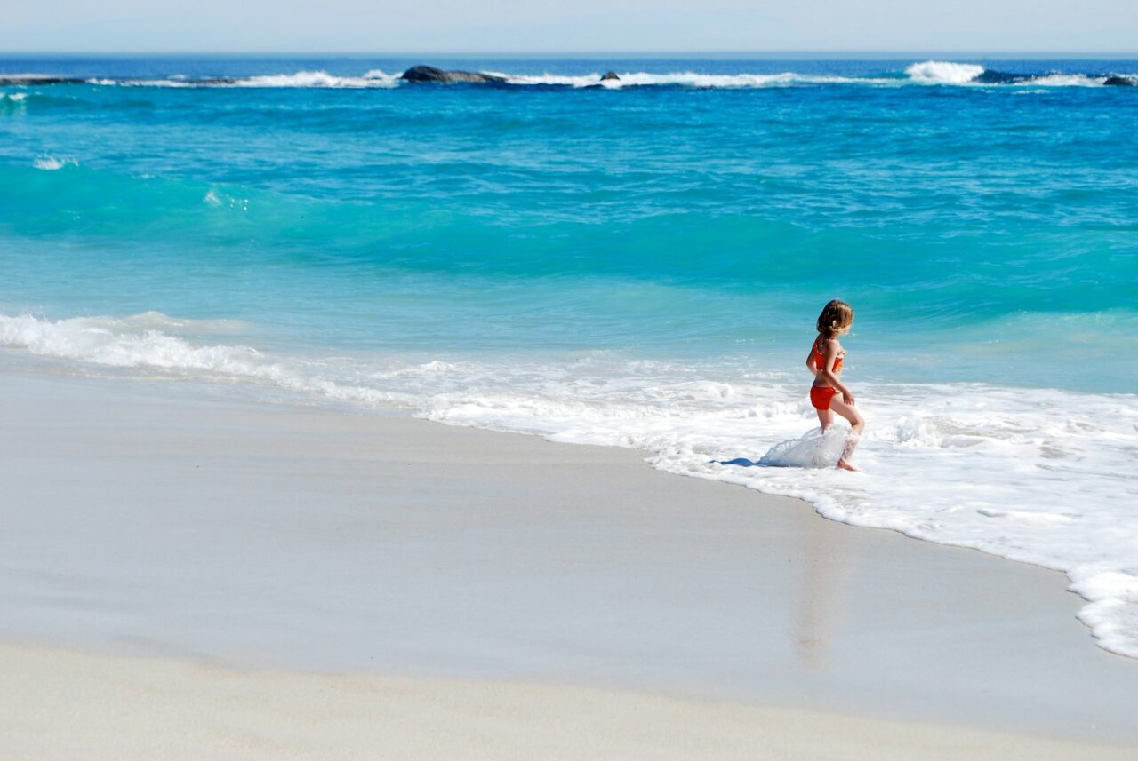 Child walking into the ocean on a white sandy beach
