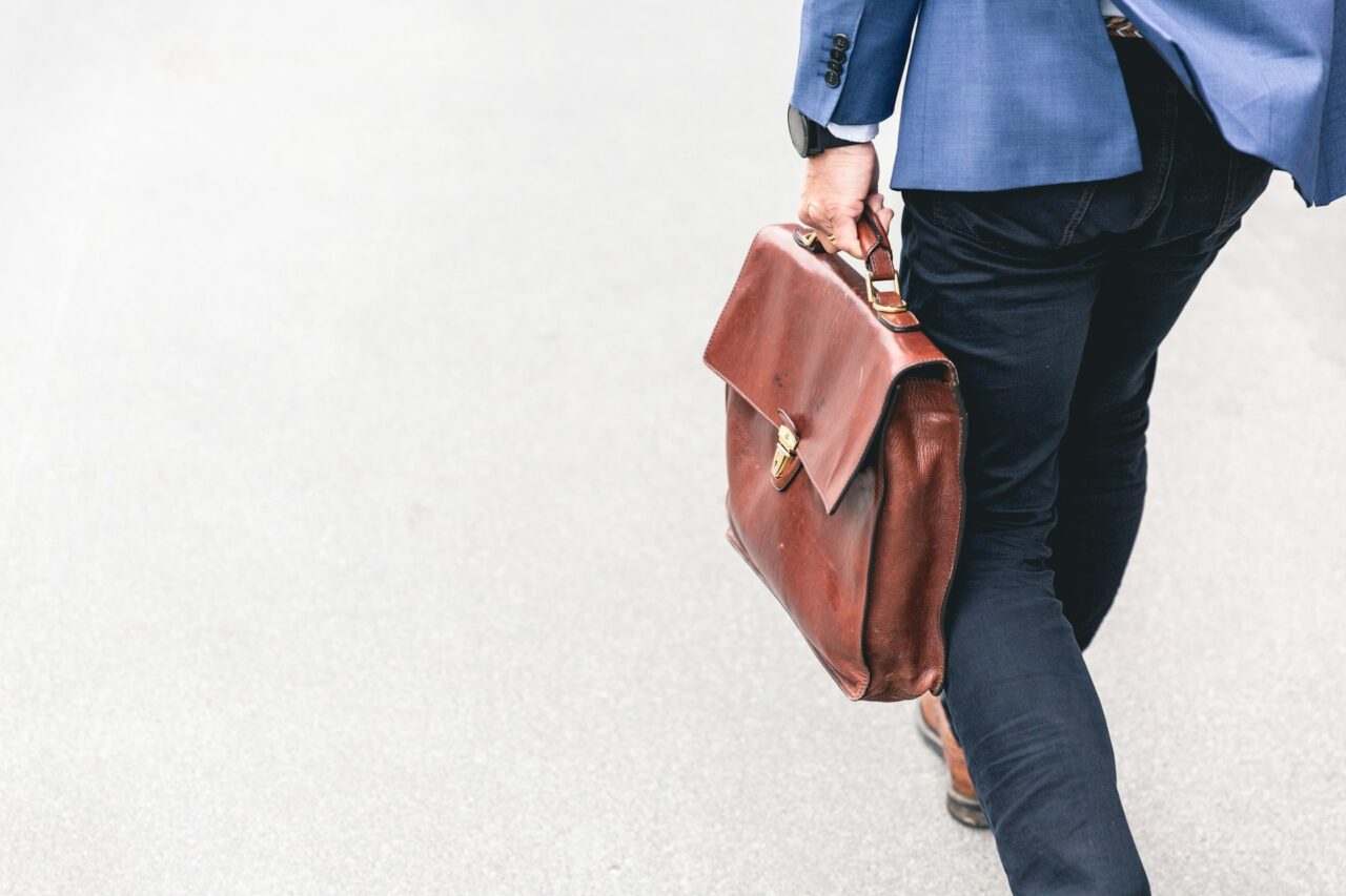 Close up of man in blue suit walking with a brown briefcase