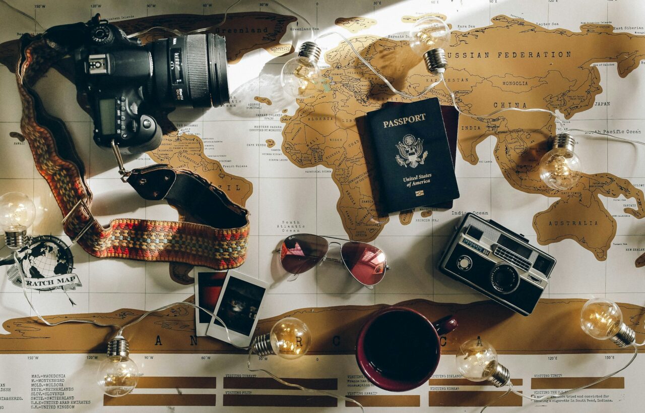 Overhead shot of a map with camera passport, sunglasses and other travel accessories