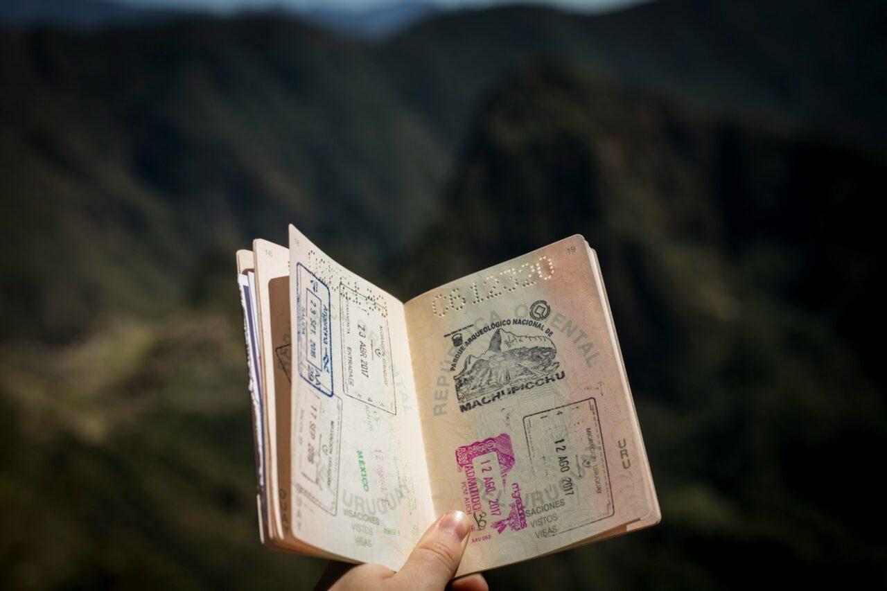 Hand holding an open passport with stamps