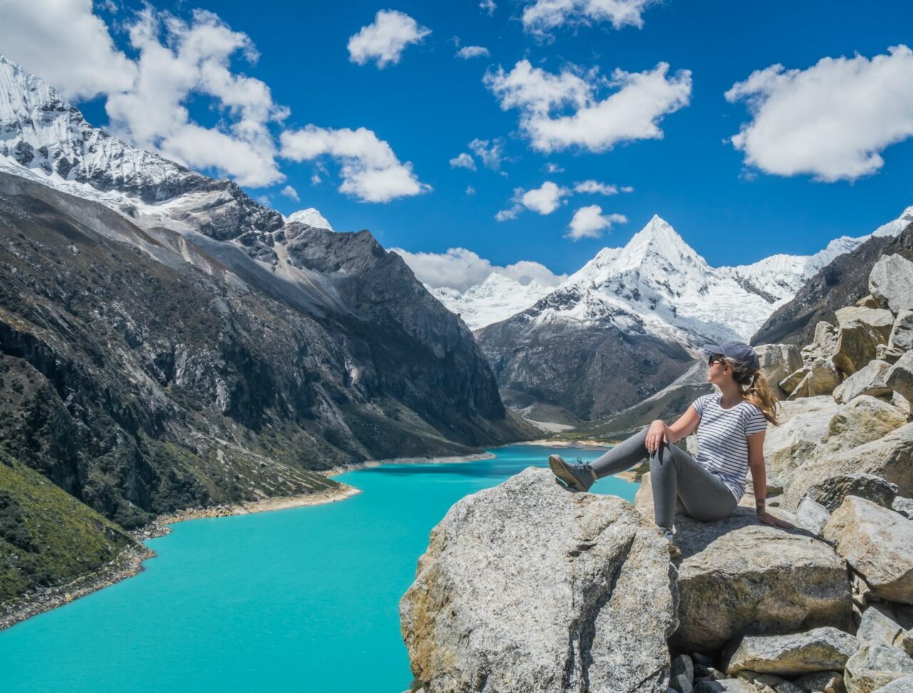Woman sitting on a rock next to Paron Lake in Peru