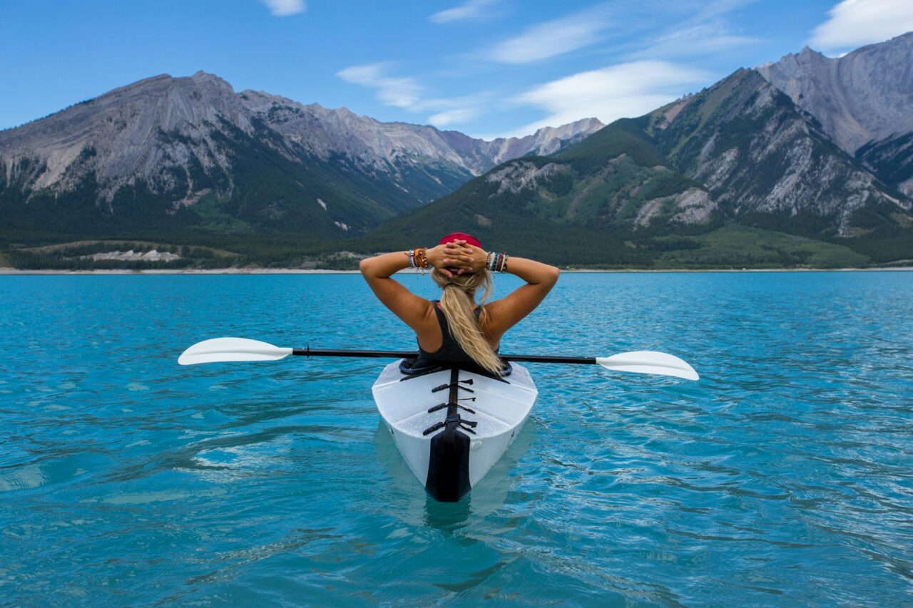Girl with blonde hair in a kayak on a lake with turquoise blue water