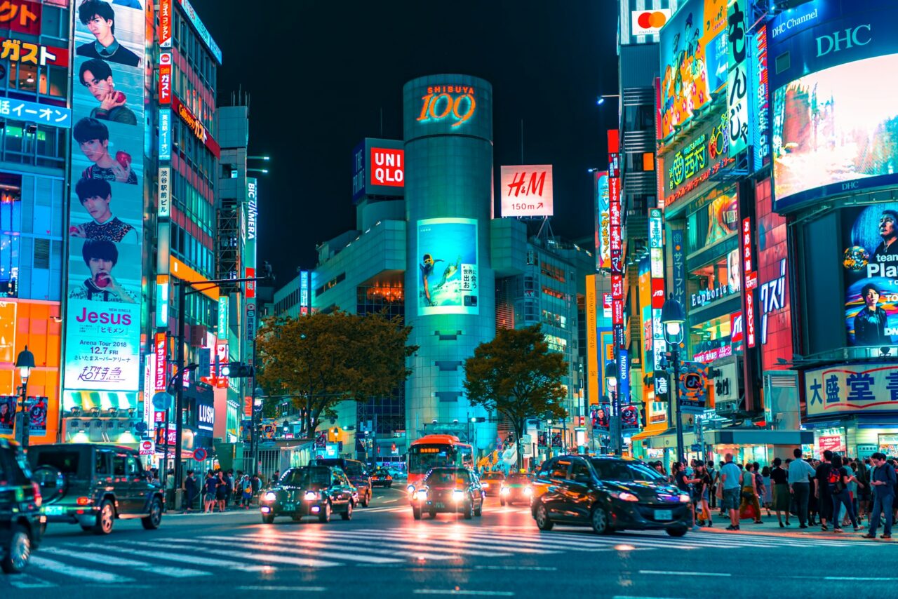 Shibuya crossing at night with cars and LED advertising boards