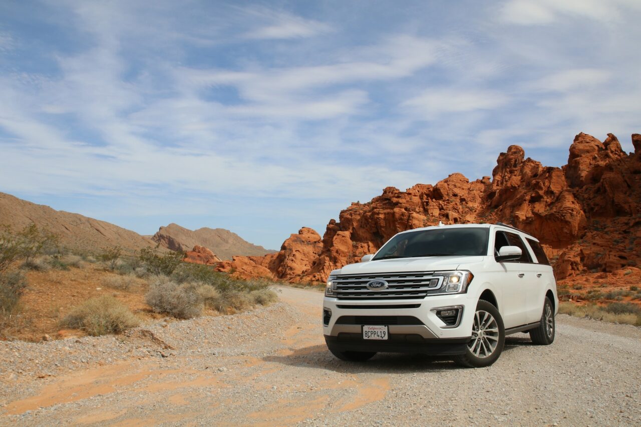 White Ford SUV parked next to red rocks in the Valley of Fire