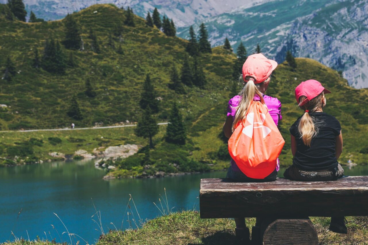 Two children sitting on a bench looking at a lake
