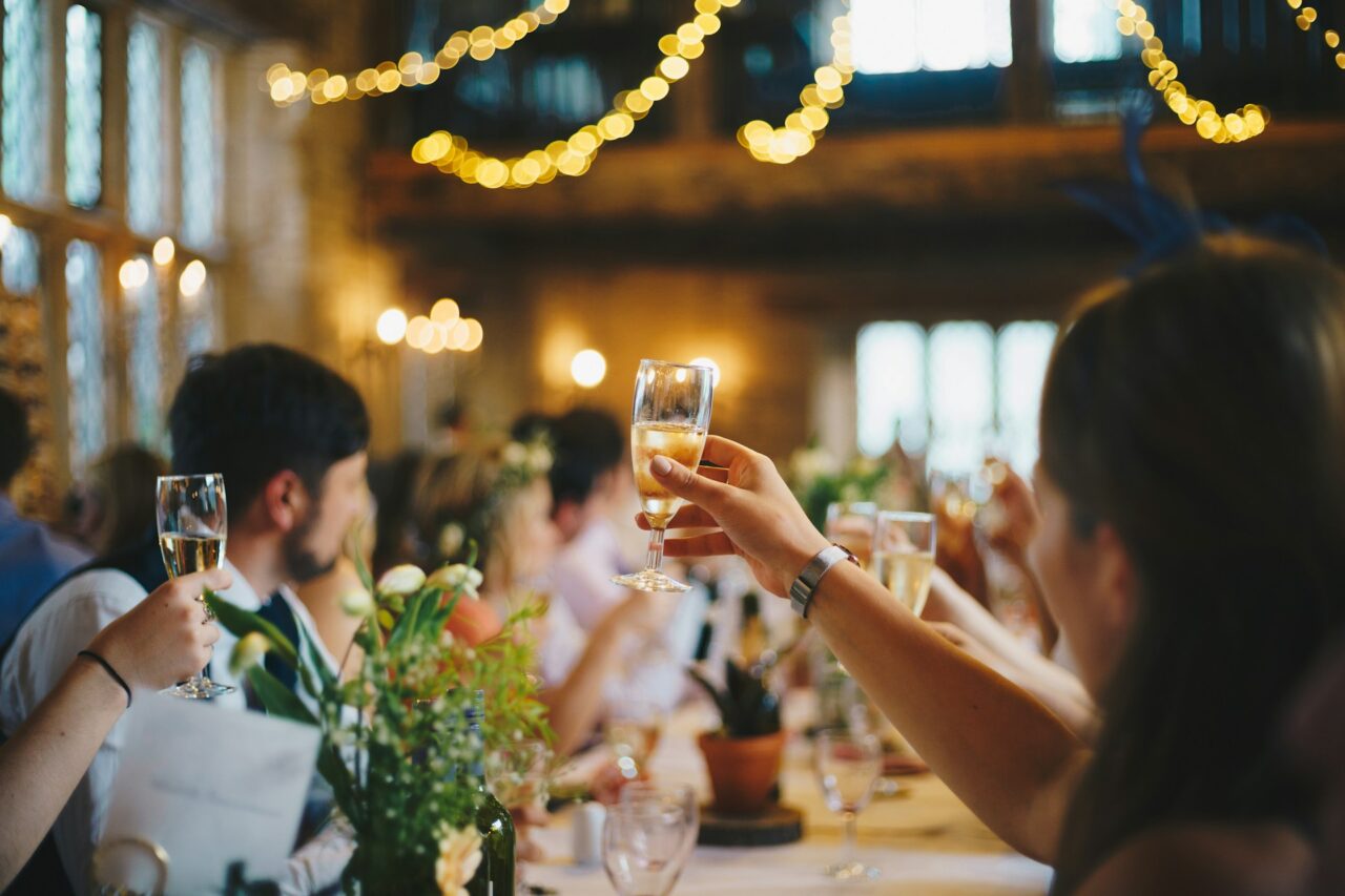 Guests sitting at a dinner table raising their champagne glasses to toast