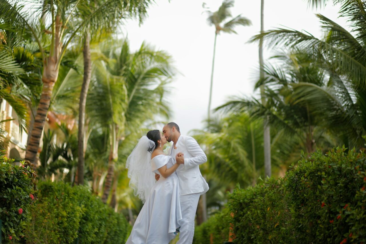 Bride and groom kissing under palm trees