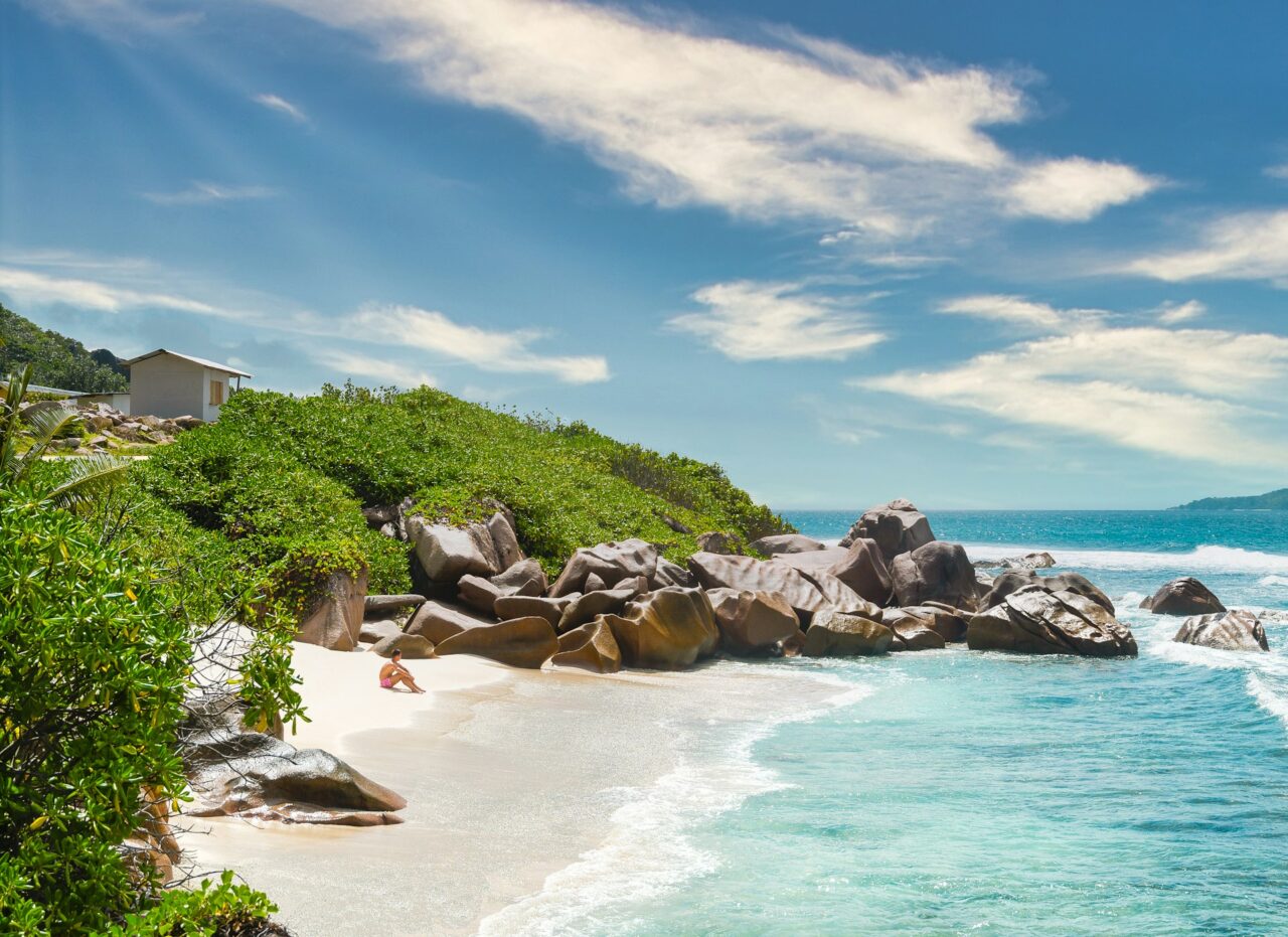 Person sitting on a white sandy beach in the Seychelles