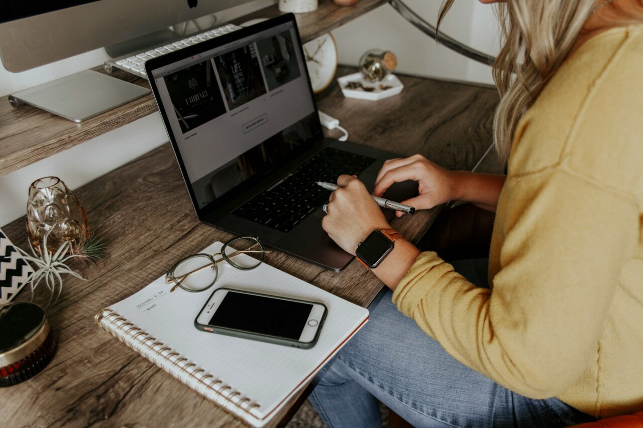 Woman working at a desk with a laptop, notebook and phone