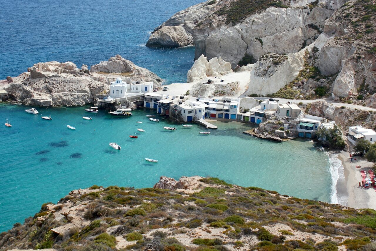 Boats on the water next to a small beach in Milos, Greece