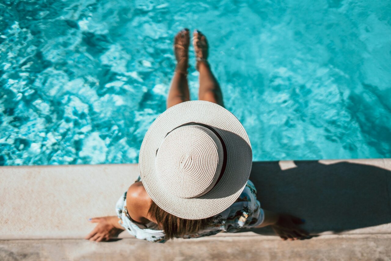 Woman wearing a hat sitting next to a pool