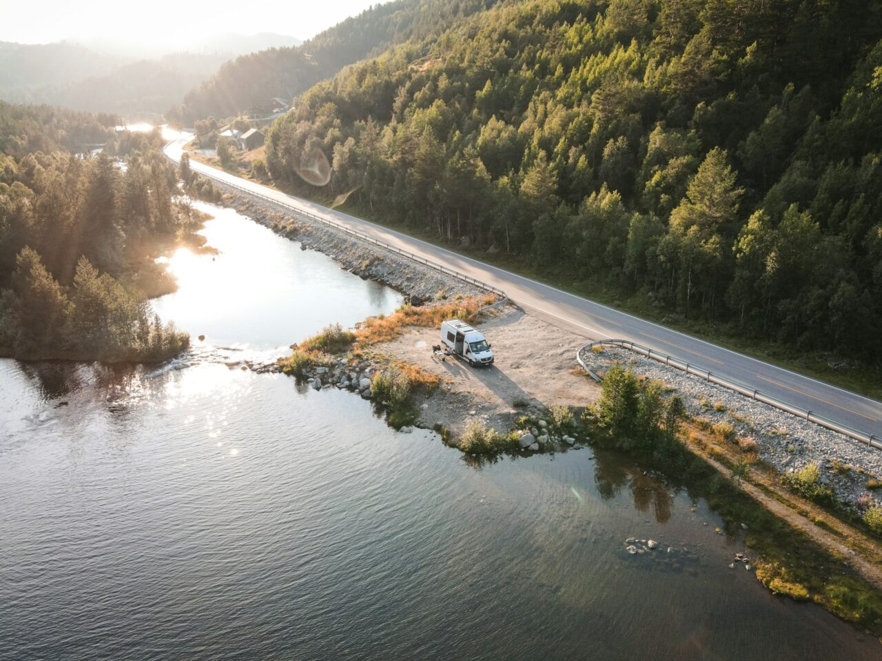 Campervan pulled up next to a scenic road with trees and lake