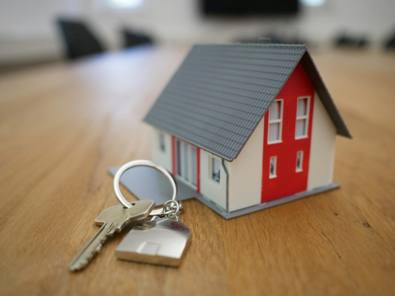 Keys next to a small model house on a wood table