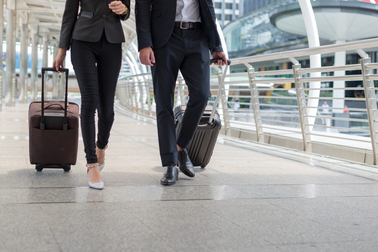 business man and business woman walk together with luggage