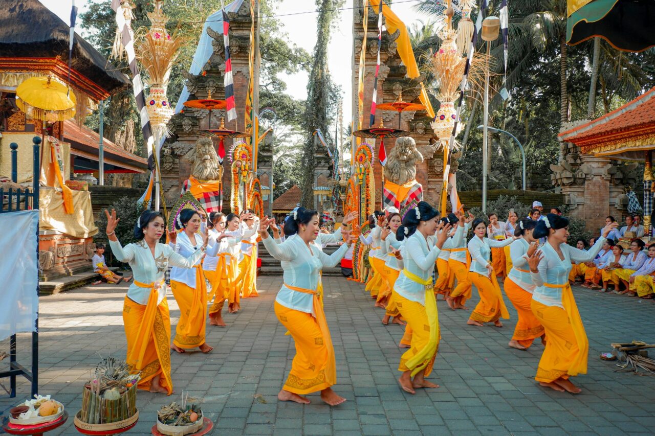 Group of women in traditional dress dancing outside a temple in Bali