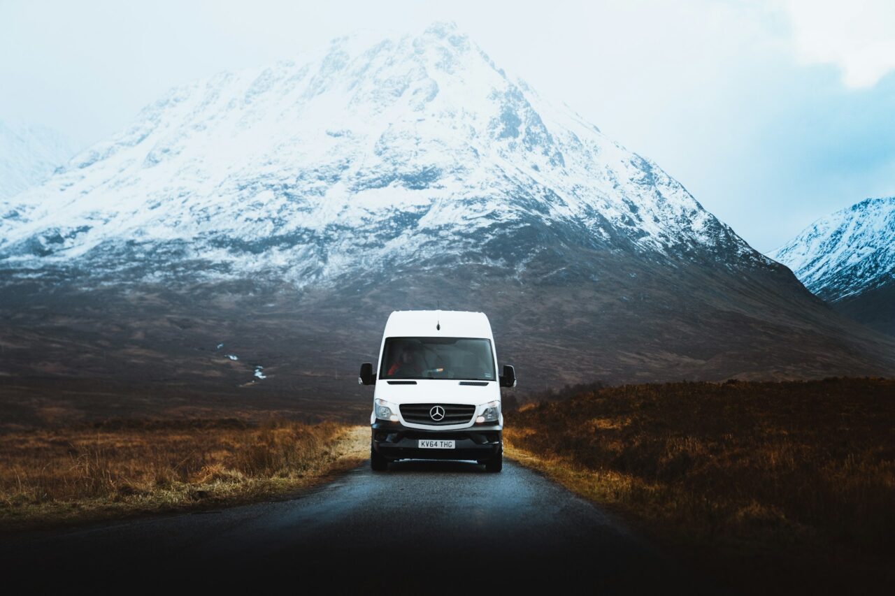 White van in front of snow capped mountains