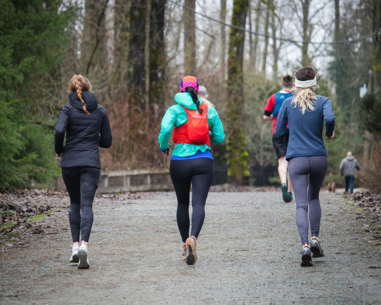 Three people running along a trail in winter