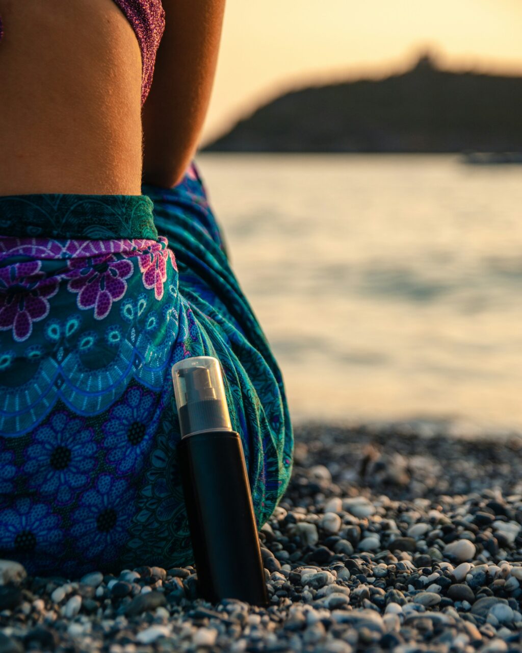 Close up of woman in a sarong next to a bottle of sunscreen