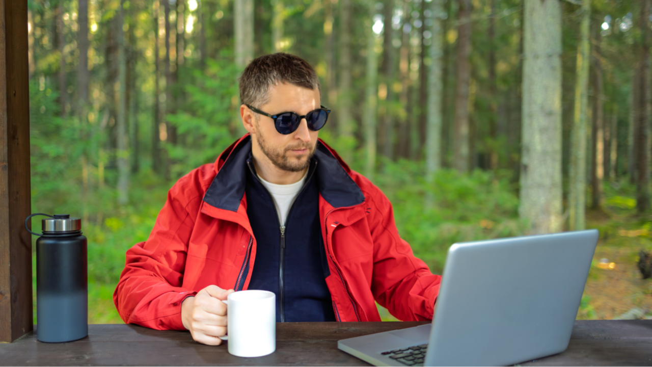 Man wearing a red jacket sitting at a desk with a laptop
